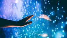A hand reaches out toward another hand with a starry blue boundary between them
