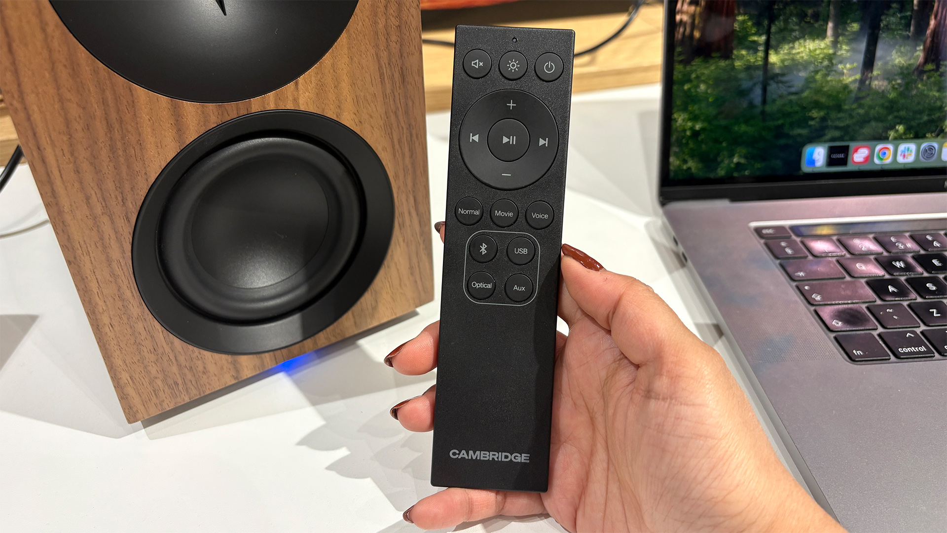 Cambridge Audio L/R S desktop speakers with remote held in hand