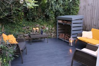dark painted decking with seating and log store