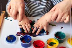 Sensory play with mother helping child to pain with their hands