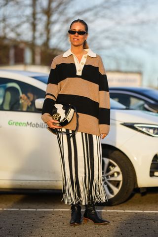 woman wearing rugby shirt, striped skirt, and boots