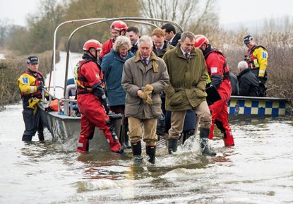 The then Prince of Wales returns from the flood hit village of Muchelney by boat as he visits flood-hit communities on the Somerset levels on February 4, 2014 in Langport, England. (Photo by Samir Hussein/WireImage)