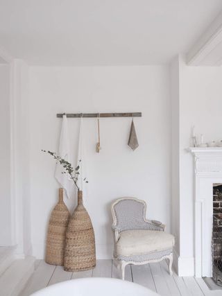 A white room with an upholstered armchair and two tall wicker vases