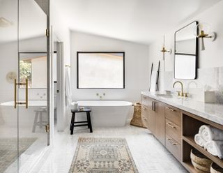 white bathroom with mosaic floor tiles, vintage rug, white tub, black stool, basket, large vanity