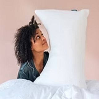 A person sitting under a Hypnia duvet with a Hypnia pillow