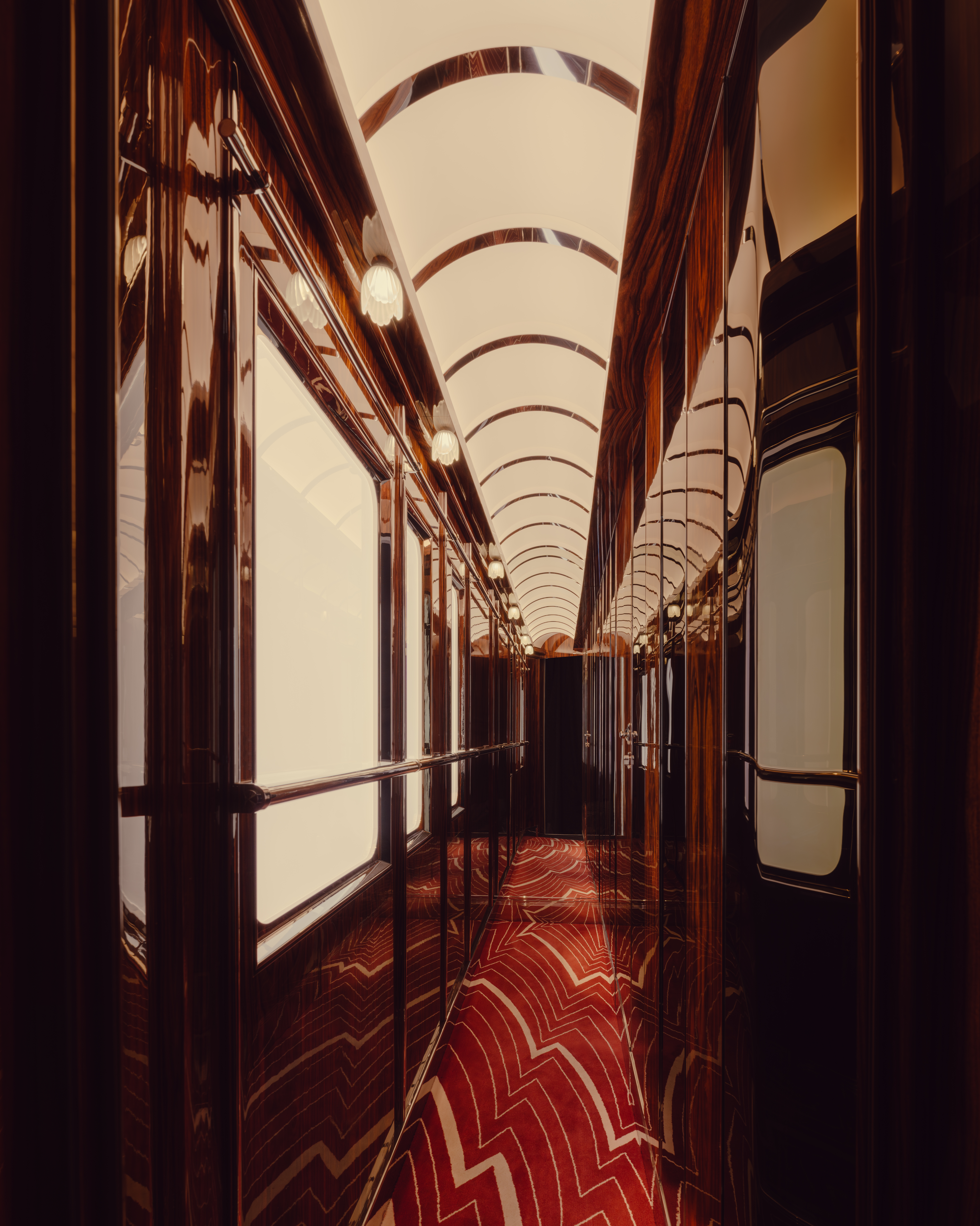 A series of images showcasing the vintage-inspired interiors of a luxury train, characterized by lacquered marquetry, plush textiles, geometrical patterns, and a chocolate, gold, cherry plum, green, and baby blue palette.