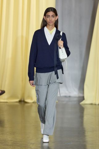 A Sandy Liang model wearing a navy sweater with a gray skirt-over-pants look at the fall/winter 2024 show.