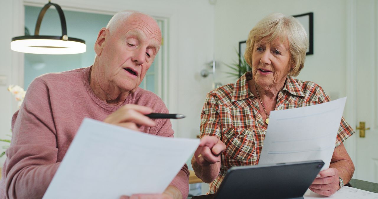 Home, talking and senior couple with paperwork, financial planning and tablet with taxes, pension fund and life policy. Documents, old man or elderly woman with insurance, conversation and investment