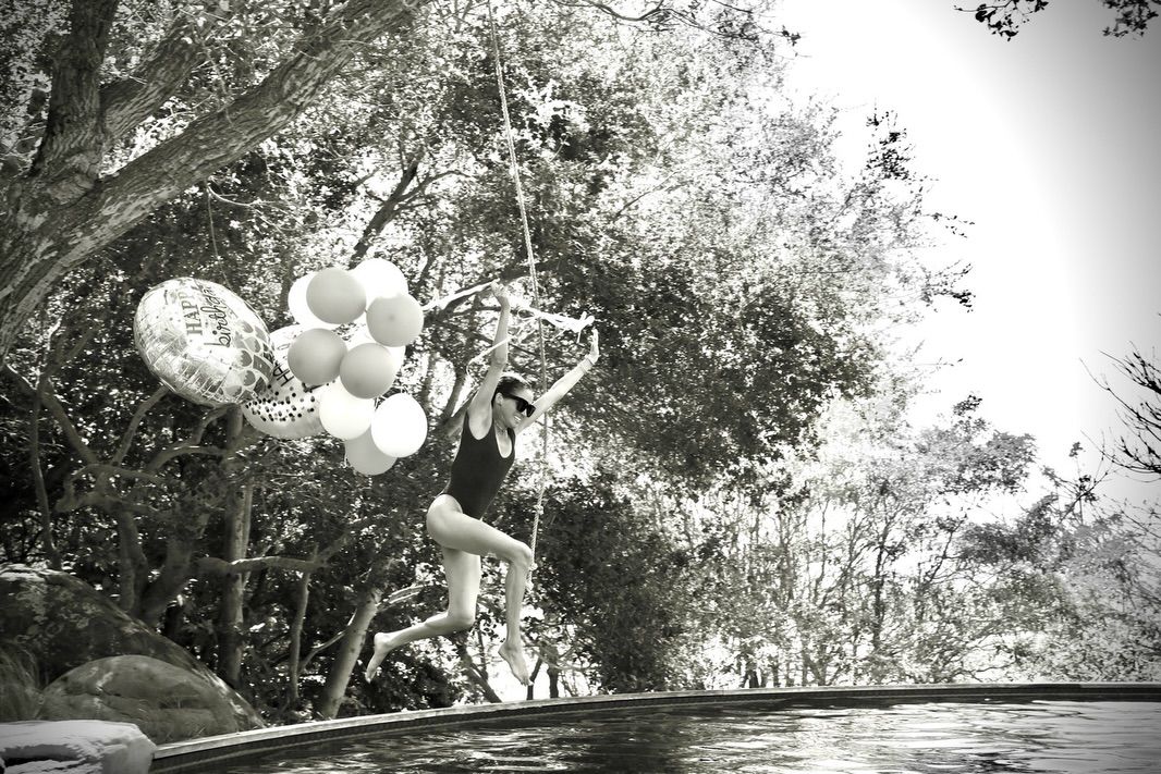 Meghan Markle jumping in a pool holding balloons