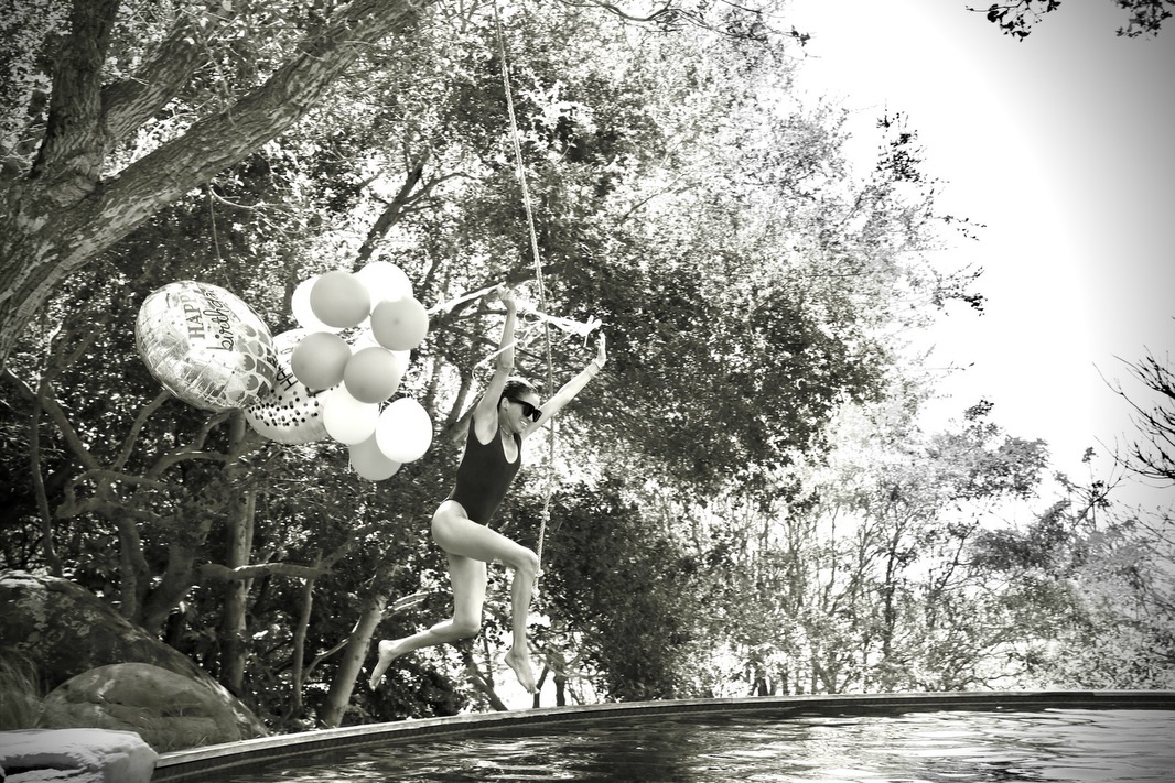 Meghan Markle jumping in a pool holding balloons