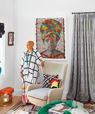 living room with white walls, gray patterned sculptural chair, patterned rug, green fleece and colorful artwork