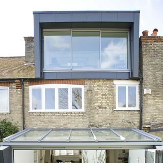 exterior of a grey modern loft conversion with frameless glass window on a brick terraced house