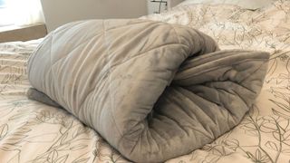 A weighted blanket folded on a bed to create a safe sleep environment.