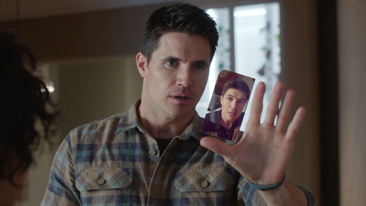 Ein Pressebild von Robbie Amell als Nathan, der Nathan auf seinem Handy in Upload ansieht.