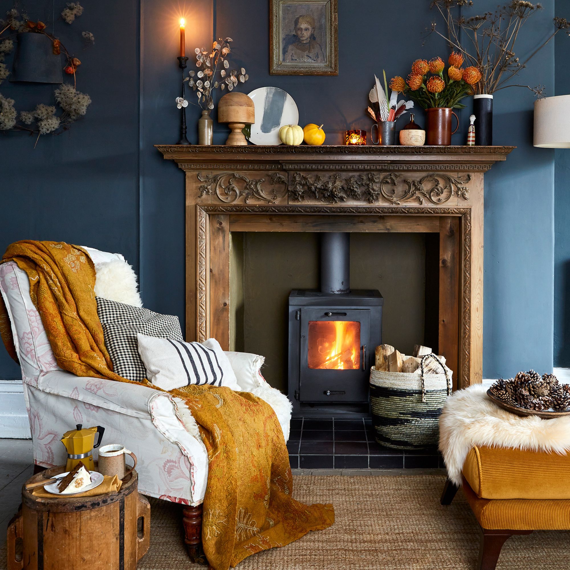 living room with dark blue walls and white ceiling and carved wooden fireplace that houses a wood-burning stove