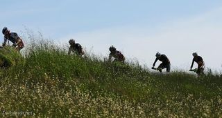 Riders cross a grassy ridge