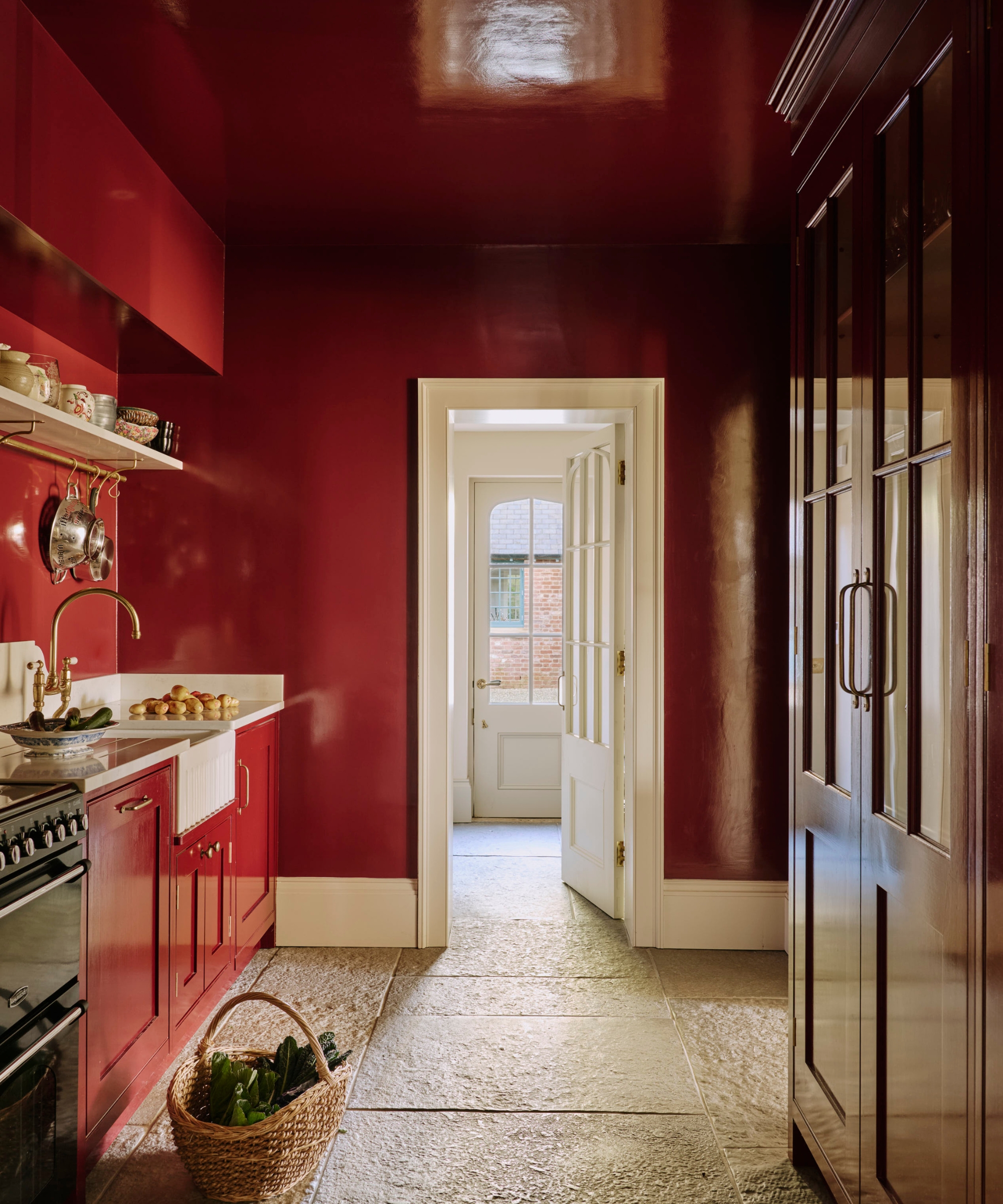 A small galley kitchen with red lacquer paint applied to the walls, cabinets, and ceiling