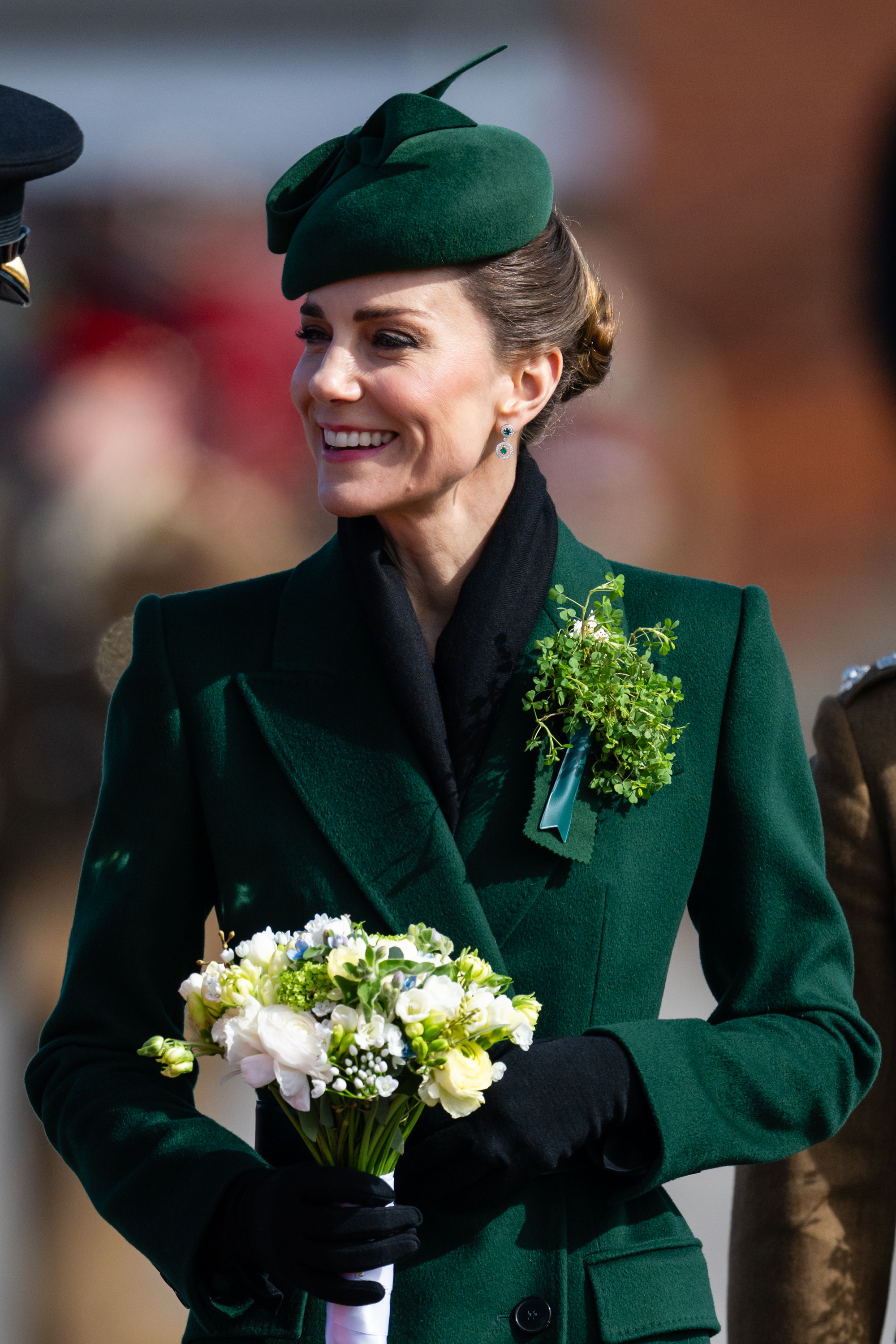 Princess Kate wearing a green coat holding flowers