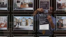 An estate agent hangs a promotional sign in the shop window