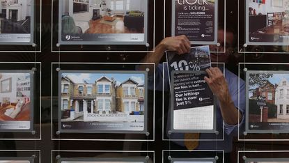 An estate agent hangs a promotional sign in the shop window