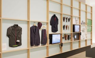 A display of cycling clothing hung on a wall with monitors with headphones