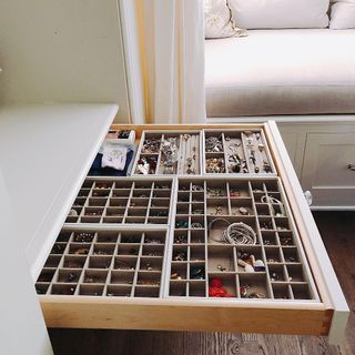 An open drawer with jewelry in drawer dividers