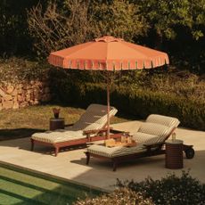 Soho Home's striped sun loungers and an orange parasol by the pool