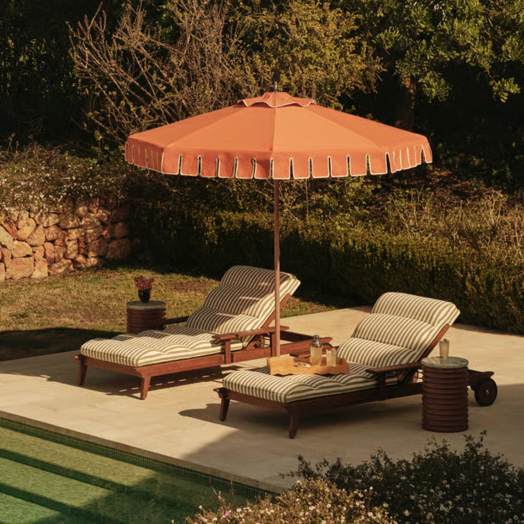 Soho Home's striped sun loungers and an orange parasol by the pool