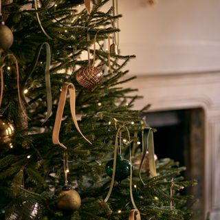 detail image of Christmas tree with gold and sage green ribbons, gold decorations, fireplace in background
