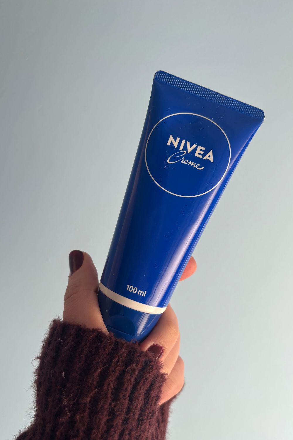 una mano sosteniendo el tubo de crema nivea