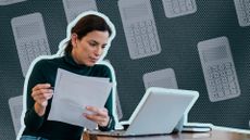 Woman sat with paperwork looking at laptop in concerned manner