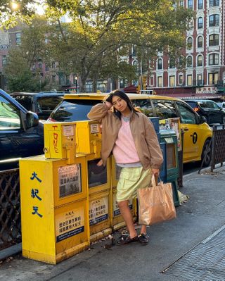 Fashion influencer Michelle Li wearing a chic fall outfit with a pastel knit and skirt, vintage-inspired jacket, and boat shoes in New York City.