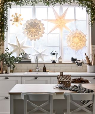 White kitchen with star lights ate the window and garland around the window frame