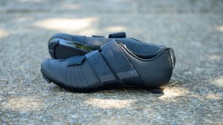 black velcro cycling shoes on a shaded cement background