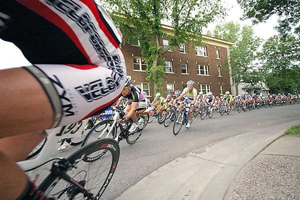 The women's field rounds a tight corner at high speed.