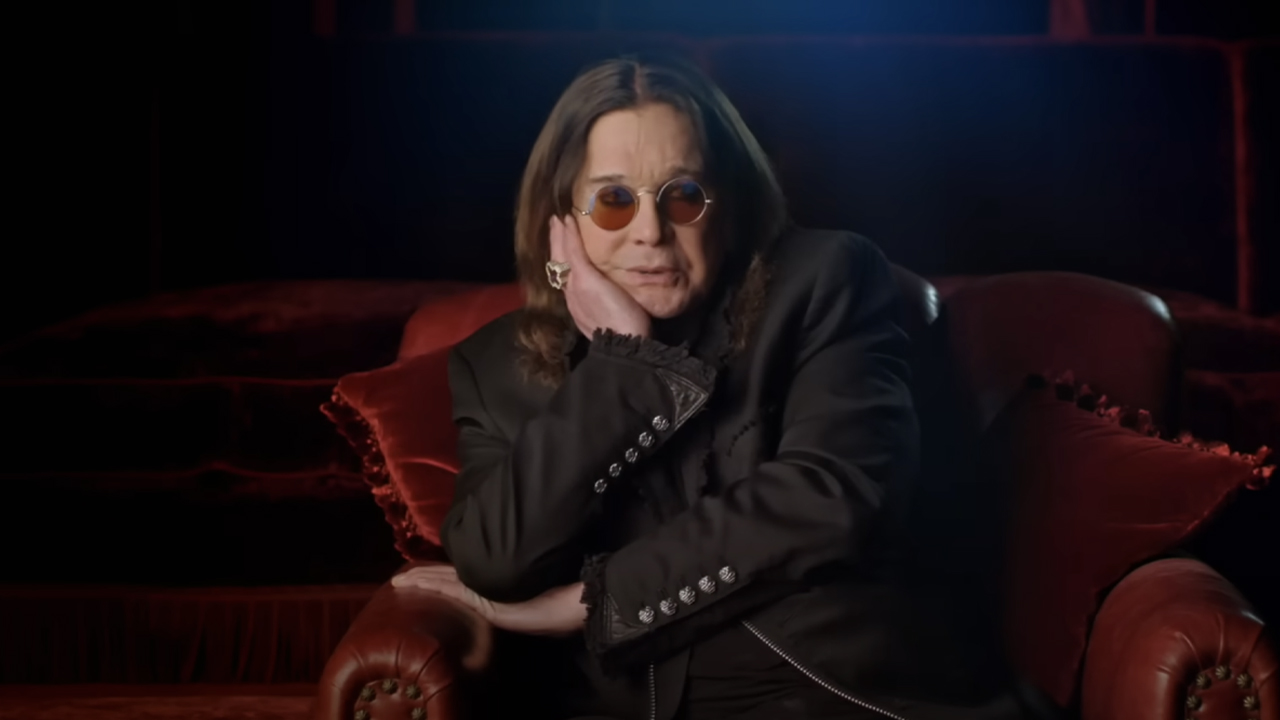 Ozzy, dressed all in black and with his trademark glasses, sitting on a velvet chair in Biographies documentary &#039;The Nine Lives of Ozzy Osbourne.&#039;