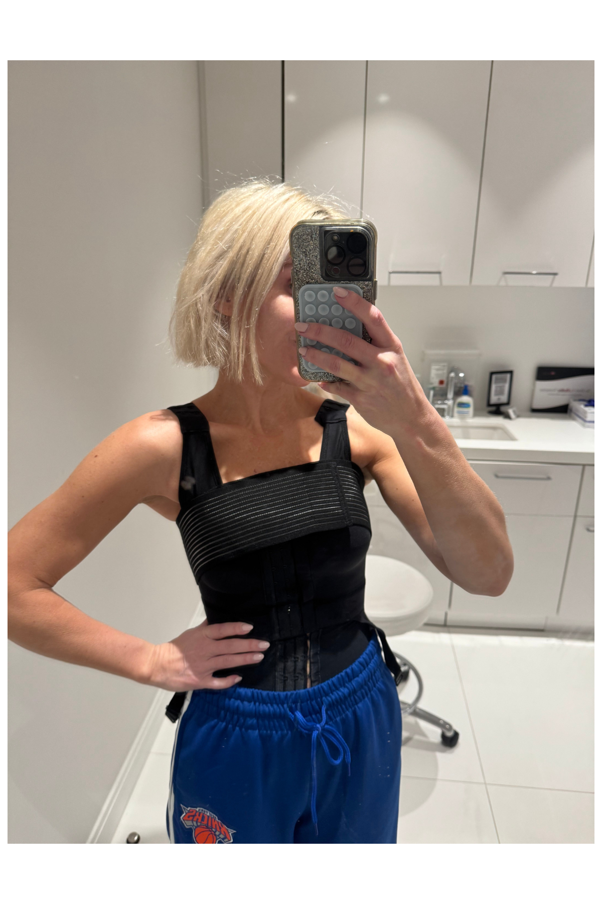 Micaela English in a black top and blue pants in a mirror selfie