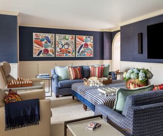 snug living space with dark blue and cream walls, blue sofas, colorful cushions and artwork