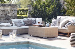 A modular rattan garden sofa by the side of a pool
