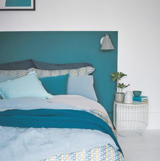 White bedroom with blue headboard with lights attached