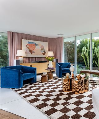 Mandy Moore's living room, including a checker-printed rug, blue velvet sofas, and pink curtains