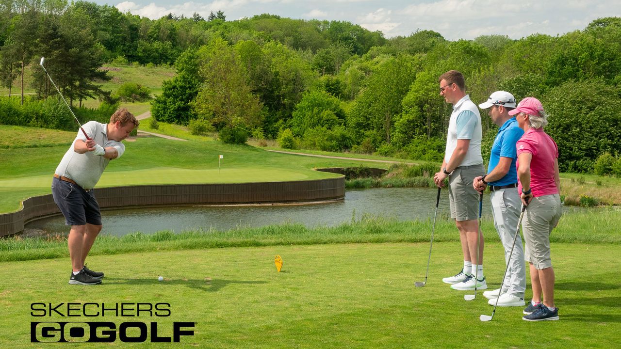 A group shot of four golfers teeing off to a par 3 green