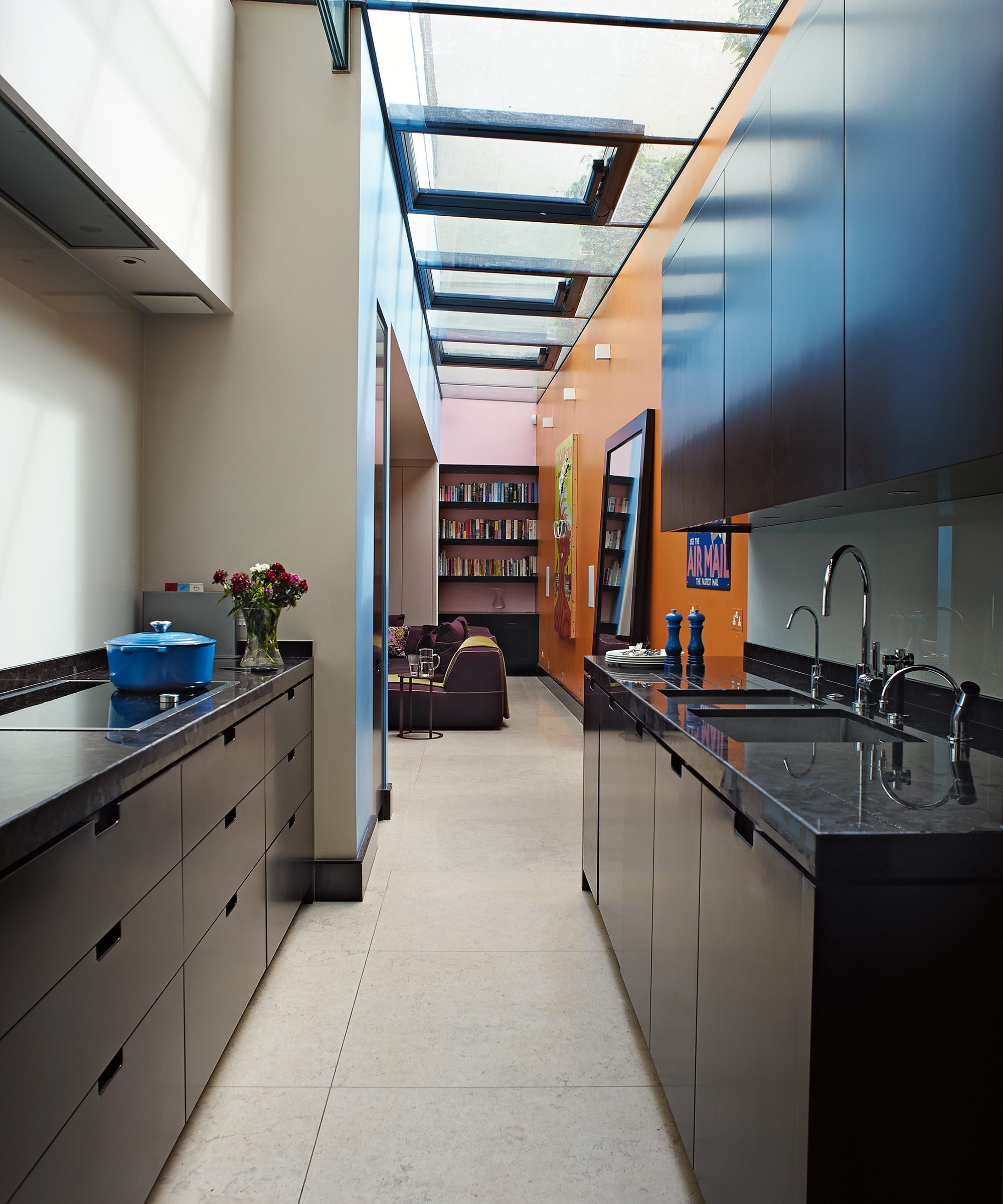 A black galley kitchen idea in a narrow room with orange wall and skylights.