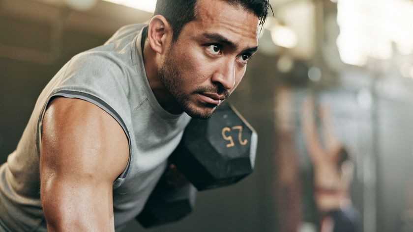 a photo of a man very focussed doing a dumbbell row