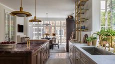A timeless kitchen with beige and brown cabinets, marble countertops, and brass accents
