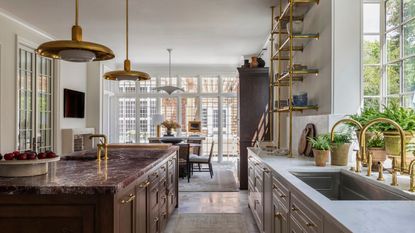 A timeless kitchen with beige and brown cabinets, marble countertops, and brass accents