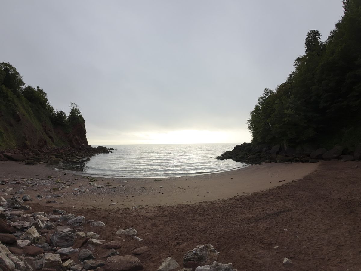 Early morning on a rocky beach with sunrise and calm seas