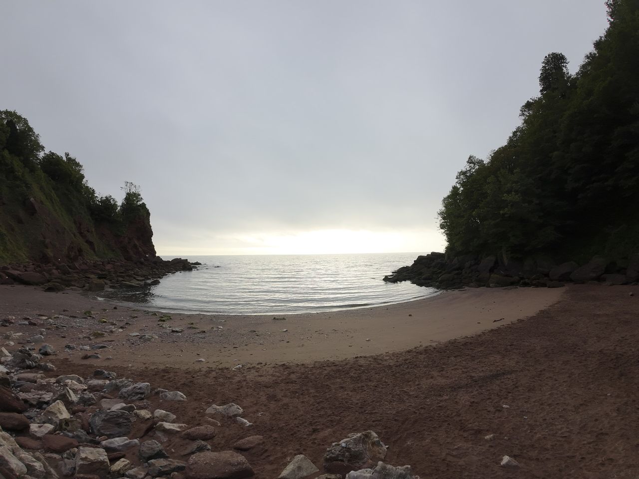 Early morning on a rocky beach with sunrise and calm seas