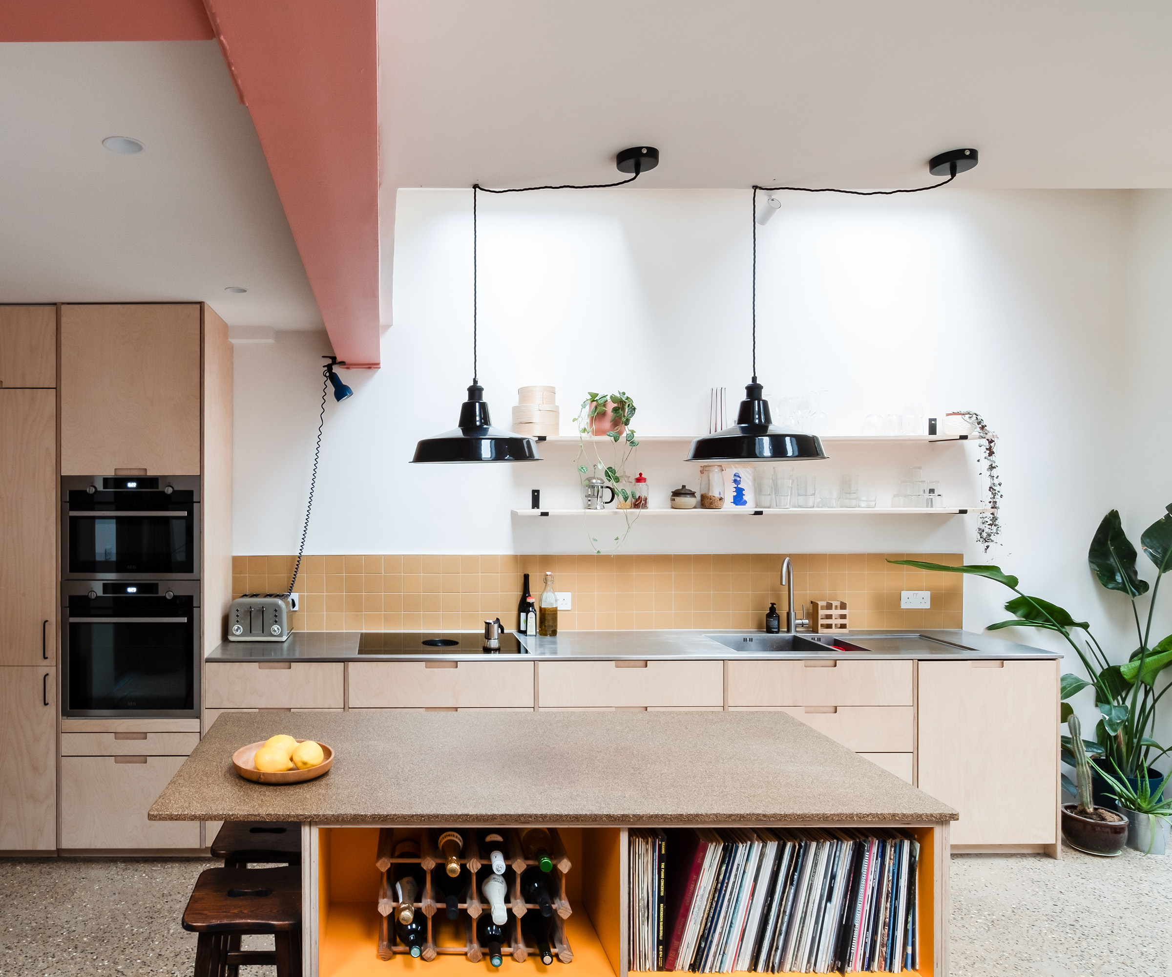 A light wooden kitchen with white walls and black pendant lights over the kitchen island