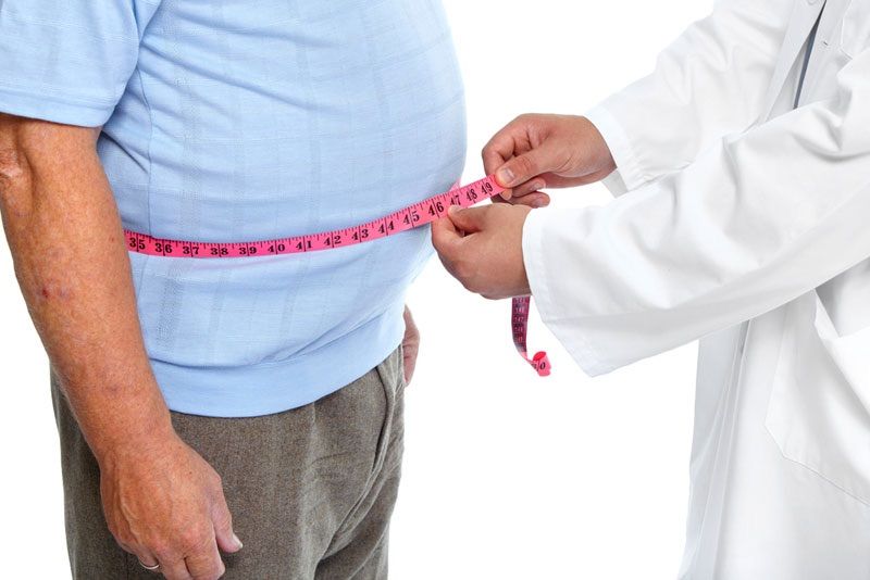 An overweight man getting his waist size measured by a doctor.